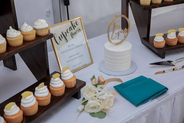 Intimate wedding cake surrounded by tropical cupcakes