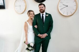 Bride and groom next to a wall of clocks at the Oxford Exchange