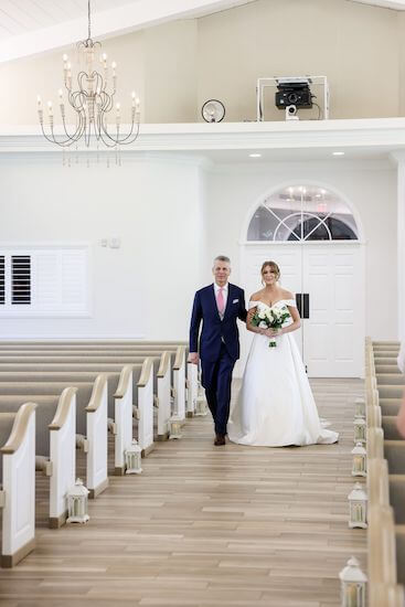 Bride being escorted down the aisle at her Harborside Chapel wedding ceremony