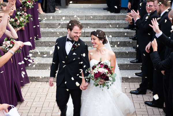 Bride and groom exit Tarpon Springs Greek Orthodox wedding under a shower of roses