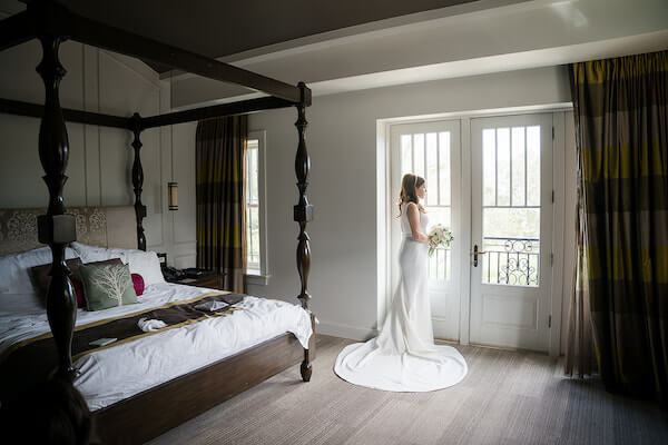 Bride standing in from¿nt of the window of her bridal suite at The Birchwood