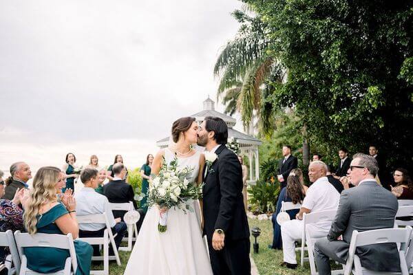 Newlyweds stop for a quick kiss as they walk up the aisle