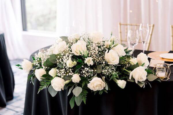 Sweetheart table decorated in black and gold overflowed with white flowers