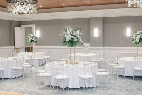 Hyatt Regency Clearwater ballroom set with clear acrylic chairs , white line and tropical greenery with white flowers