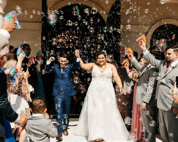 Bride and groom under a shower of bubbles after their wedding ceremony