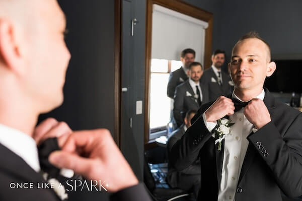 Groom looking in the mirror while fixing his tie