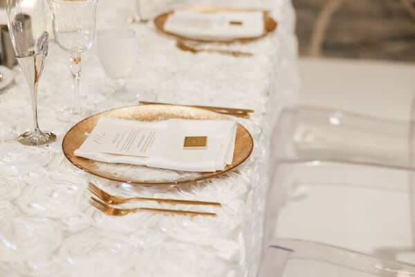 Gold charges and flatware accent a white and champagne downtown Tampa wedding