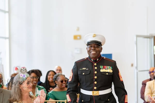 Smiling groom walking down the aisle in his dress blue uniform.