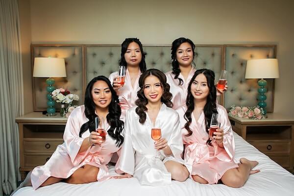 Bride in he wedding robe toasting with her wedding party.