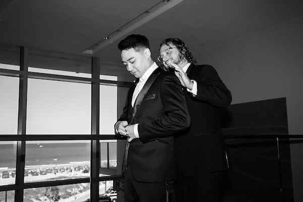 The best man helping the groom get dressed for his wedding ceremony.