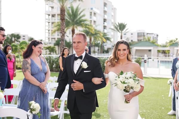 Bride walking across the lawn of the Belleview in with her father.