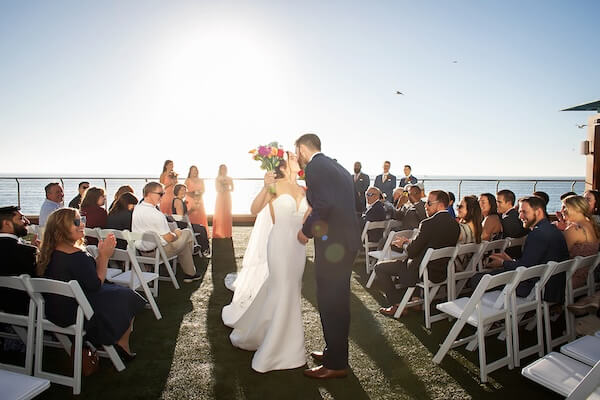 Bride and groom stop for a kiss at the end of their Opal Sands wedding.