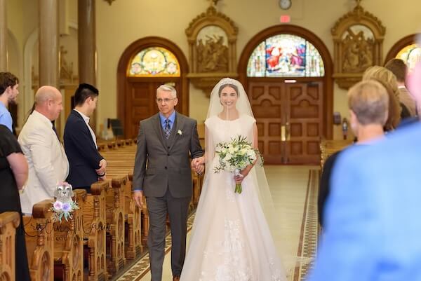 A bride walking down the aisle during her afternoon wedding ceremony.