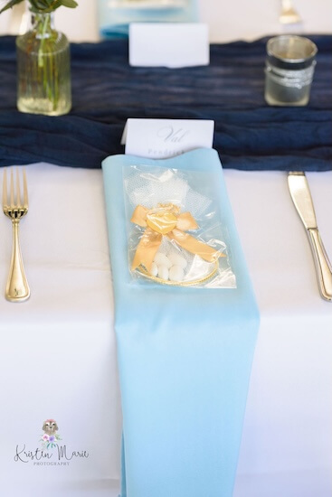 A napkin in a light blue waterfall fold with a sachet of jordan almonds for a Tampa afternoon wedding reception at Davis Islands Garden Club.