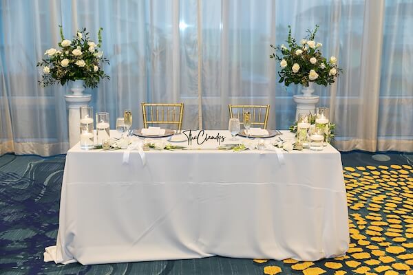 A beautiful sweetheart table dressed in white, and green with gold accents.