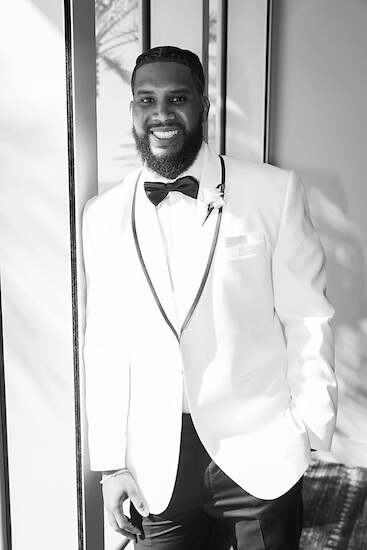 A handone groom in a white dinner jacket.