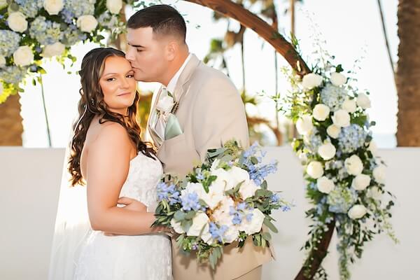 Bride and groom in front of a floral moon gate ceremony structure at the Wyndham Grand CWB.