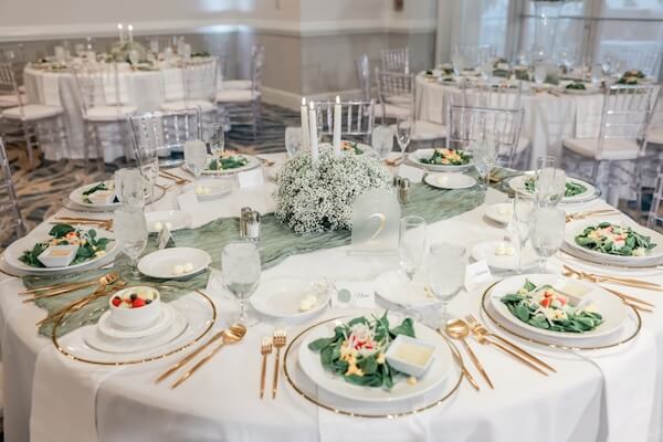 A white, gold, and sage wedding reception overflowing with baby's breath.