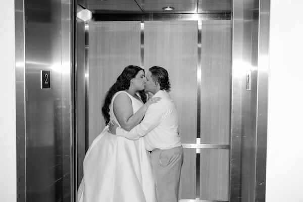 A bride and groom kissing in an elevator