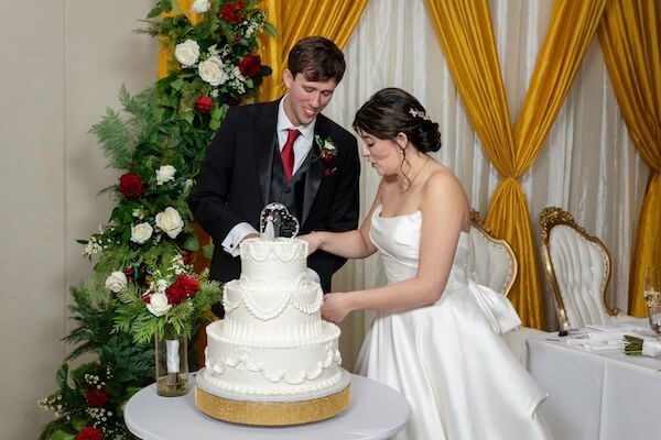 A newlywed couple cutting their wedding cake.
