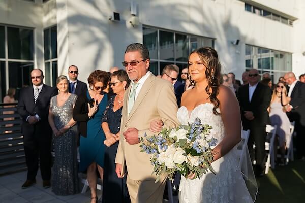 A bride walking down the aisle with her father at the Wyndham Grand Clearwater Beach.