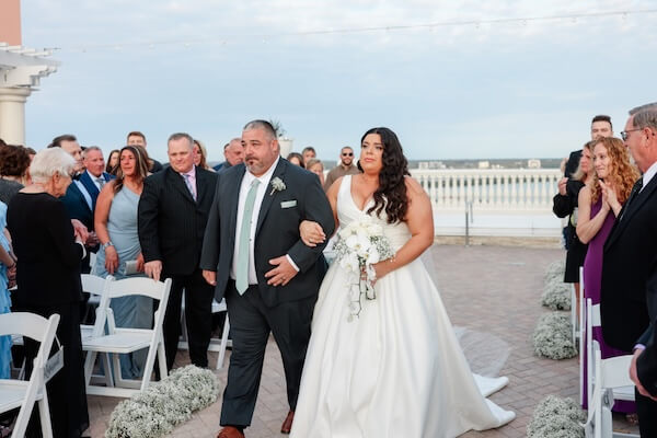 A bride and her father are walking down the aisle.