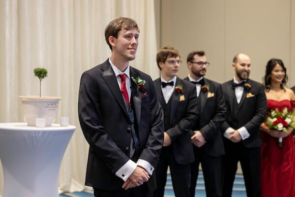 A groom looks on as his bride walks down the aisle.