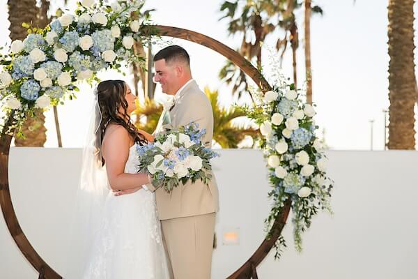 Bride and groom in front of a floral moon gate ceremony structure at the Wyndham Grand Clearwater Beach.