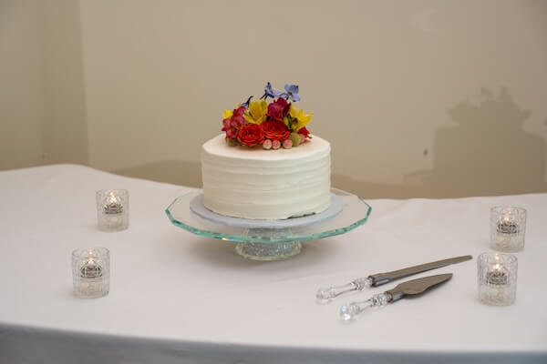 An intimate wedding cake with brightly colored flowers.
