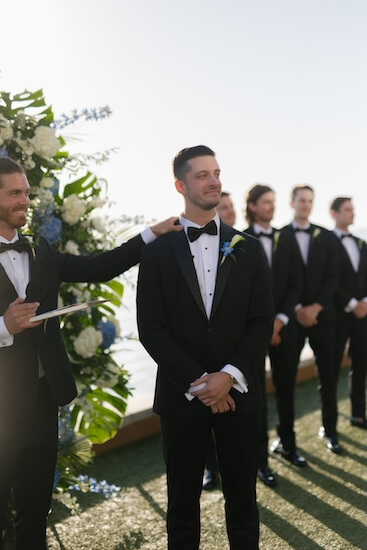 A groom looing on as his bride walks down the aisle.