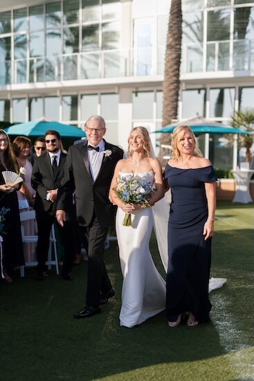A bride adn her parents walking down the aisle.