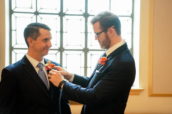 The Best Man is pinning a boutonnière on the groom before his St. Pete wedding.