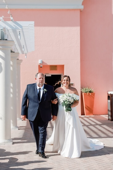 A birde walking down the aisle of her Clearwater Beach wedding escorted by her father.