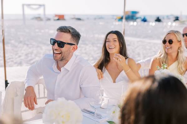 A newlywed couple laughing at toasts during their Clearwater Beach wedding reception.