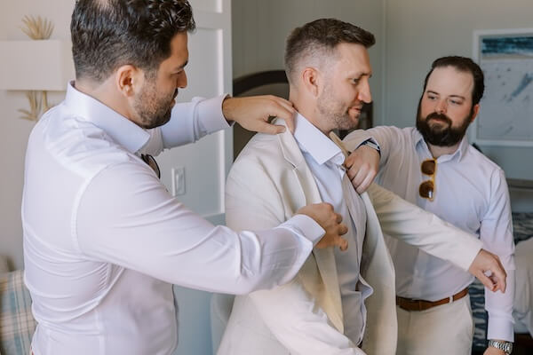 Groomsmen helping the groom get ready.