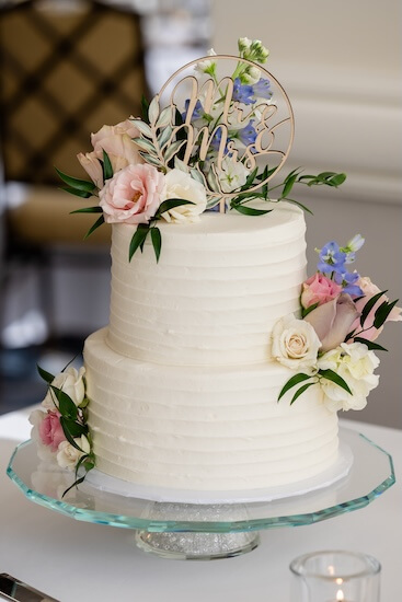 A two-tiered wedding cake with fresh flowers.