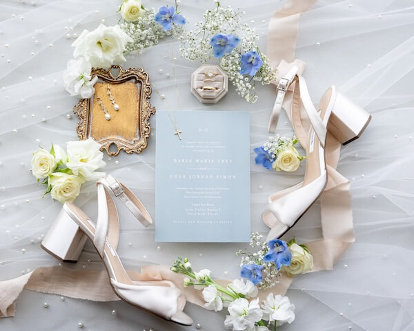 Light blue and white wedding invitation and bridal accessories.