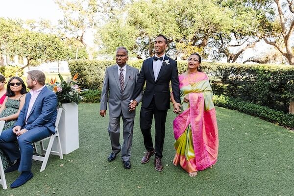 A groom waalking down the aisle with his partent for his Tampa Garden Club wedding.