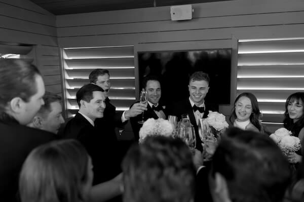 A bride and groom toating with their wedding party.