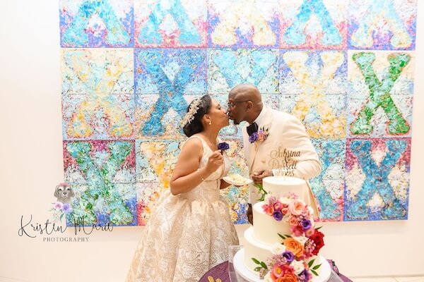 Bride and groom mkissing after cutting their wedding cake.