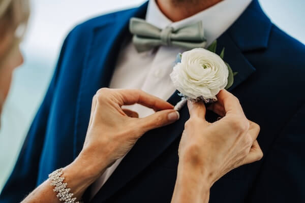 A groom's mother pinning on his boutonnière.