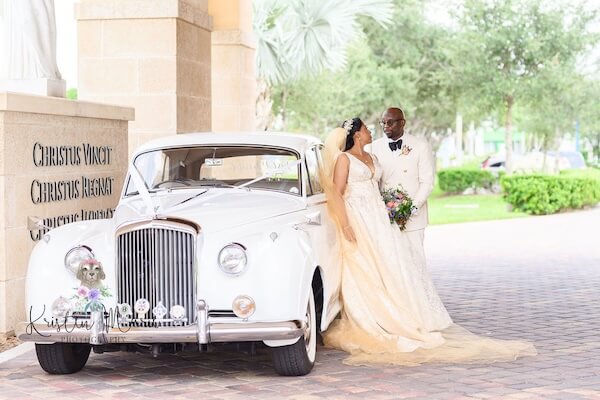 A bride and groom taking wedding portraits with a 1961 Bentley SII.